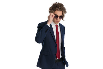 cool fashion man in suit with hand in pocket wearing and adjusting sunglasses