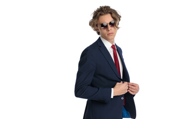 side view of sexy businessman with sunglasses buttoning suit