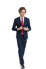 cool elegant businessman looking away while buttoning suit