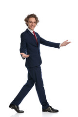 side view of enthusiastic young man showing to side and inviting