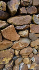 Beautiful background pattern image of a wall made of round stone red color rocks. Texture