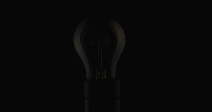 Light bulb with weak spark trying to light itself up from the shadows