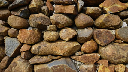 Beautiful background pattern image of a wall made of round stone red color rocks. Texture