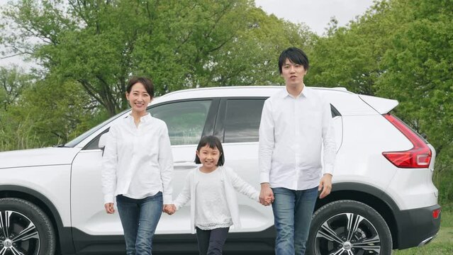 車の前で手を繋ぐ家族