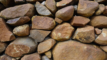 Beautiful background pattern image of a wall made of round stone red color rocks. Texture