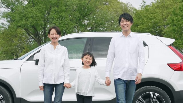 車の前で手を繋ぐ家族