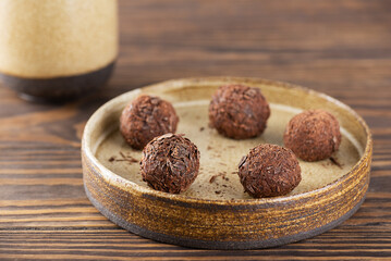Candy brigadeiro truffles with chocolate on a plate on a brown wooden table, brazilian sweets.