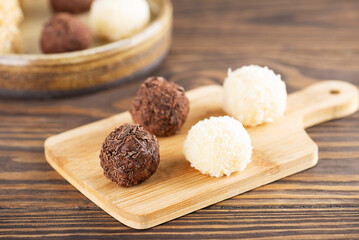 Candy brigadeiro truffles with chocolate and coconut on a wooden board, traditional brazilian sweets.