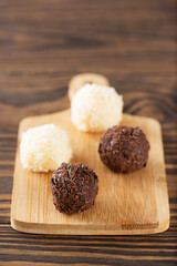 Candy truffles brigadeiro with chocolate and coconut on a brown wooden table, traditional brazilian sweets.