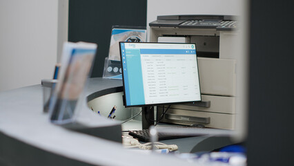 Empty hospital reception desk with computer and medical forms to make healthcare appointments and checkup visits. Registration counter at health center facility lobby, consultation exam.
