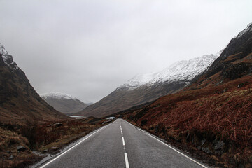 Long straight road in the mountains. Visiting the highlands in Scotland, UK. 