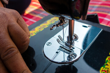 february 12th 2022, Dehradun City India. Hands operating manual Sewing machine needle bar with thread.
