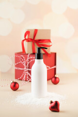 Mockup of a white dispenser with a cosmetic product on the snow against the background of Christmas gifts. 