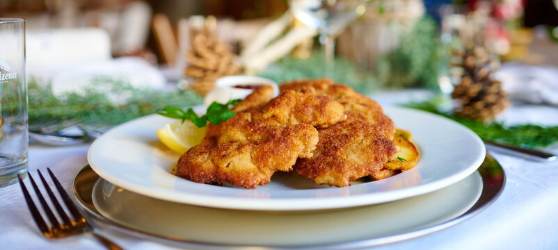 Wiener Schnitzel mit Bratkartoffeln Close Up  Panorama Breitbild an einem fein gedeckten Tisch mit Dekoration