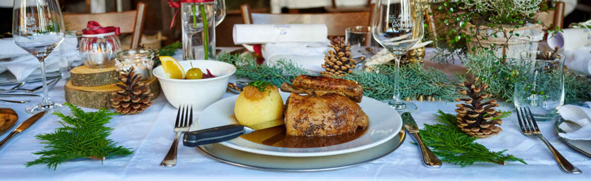 Gegrillte Ente zu Weihnachten an einem festlich gedeckten Tisch und mit reichlich Deko geschmückt