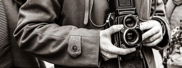 Horizontal banner or header with Hipster guy with the vintage camera photographing people in the city - Photojournalist with a famous retro camera taking photo in the crowd during street demonstration - obrazy, fototapety, plakaty