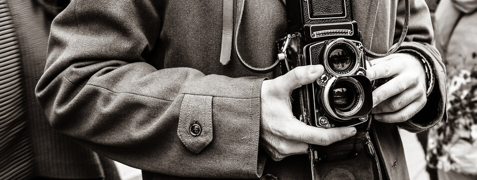 Horizontal banner or header with Hipster guy with the vintage camera photographing people in the city - Photojournalist with a famous retro camera taking photo in the crowd during street demonstration