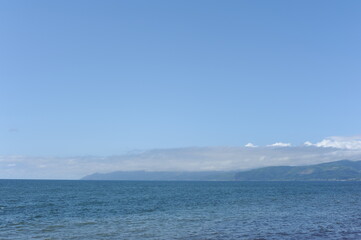 Fototapeta premium Picturesque seashore with beach and ocean waves and horizon on a sunny day with clear blue sky and calm ocean in Hokkaido, northern Japan, Asia