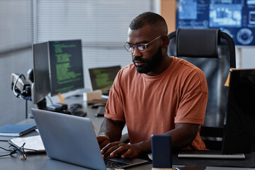Portrait of black software engineer using computer in high technology office, data systems and...
