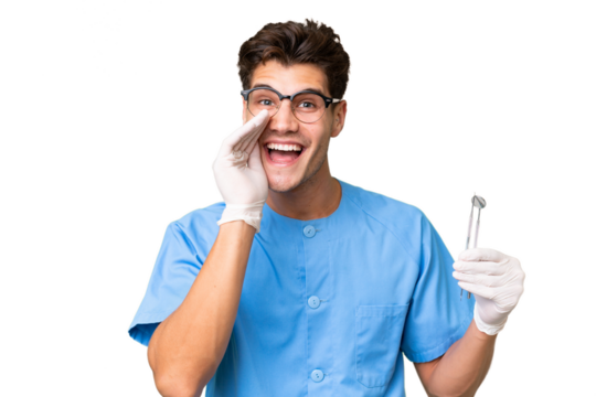 Young dentist man holding tools over isolated background shouting with mouth wide open