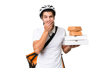 Young caucasian man with thermal backpack over isolated background happy and smiling covering mouth with hand