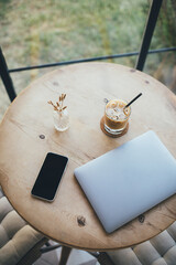 Laptop and coffee on wooden table in cozy interior.