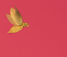 Bird made of yellow autumn leaves on red background