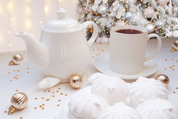   Winter, Christmas, New Year decorations composition, concept, background. White Mug, cup of tea, coffee, steam, meringue on Christmas Tree background. Christmas greeting card. Interior design.