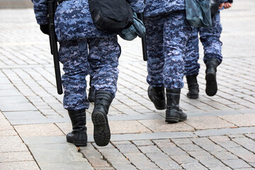 Legs of soldiers of military forces in camouflage, men walking down the city street