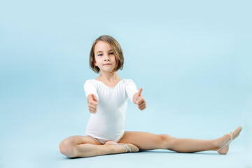 Tired girl in a white leotard sitting in half splits, giving thumbs up