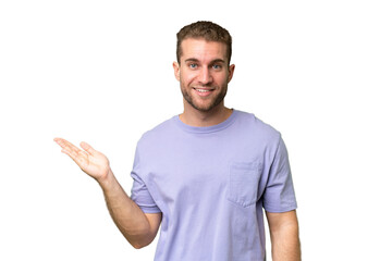 Fototapeta premium Young handsome caucasian man isolated on green chroma background holding copyspace imaginary on the palm to insert an ad