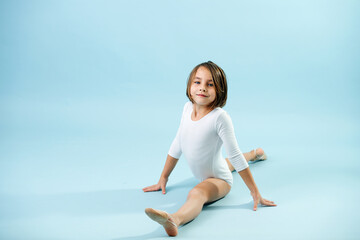 8yo girl in a white leotard doing splits, looking at the camera.