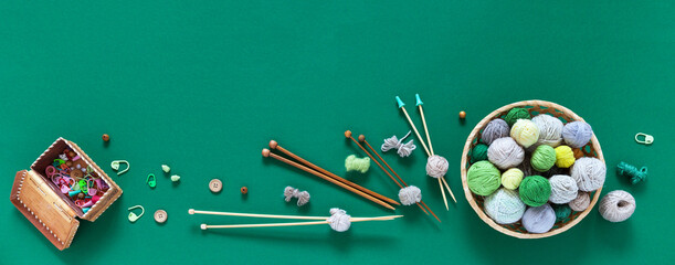 Accessories for needlework and knitting on green background: wicker basket with balls of yarn, set...