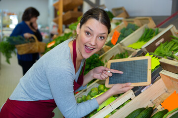 female worker holding a blackboard in a fruit store