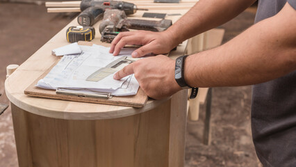 A contractor points to the perspective drawing of a custom solihiya shoe bench to be built at a furniture workshop.
