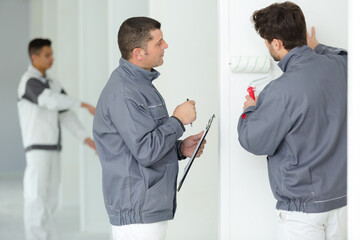 teacher supervising apprentice using roller brush