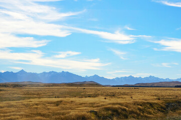 Fototapeta na wymiar Scenic blue shaded mountain range and dry farmland under bright blue autumn sky.