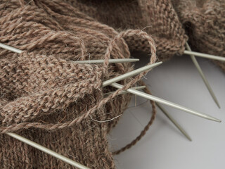 Brown socks hand made of sheep wool. Top view photo of knitted socks, needles and ball of warm yarn. Winter hobbies concept.