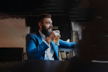 Young adult stylish man with a beard holding a pint glass of beer smiling