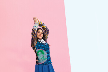 Woman with colorful dress and hands up on pink background