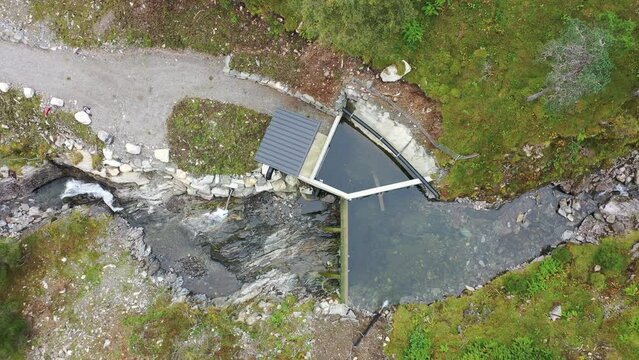 Birdseye view of a small water intake to river base hydroelectric powerplant at Markaani plant in Vaksdal Norway - Top down view from intake to water pipe high up in the mountains