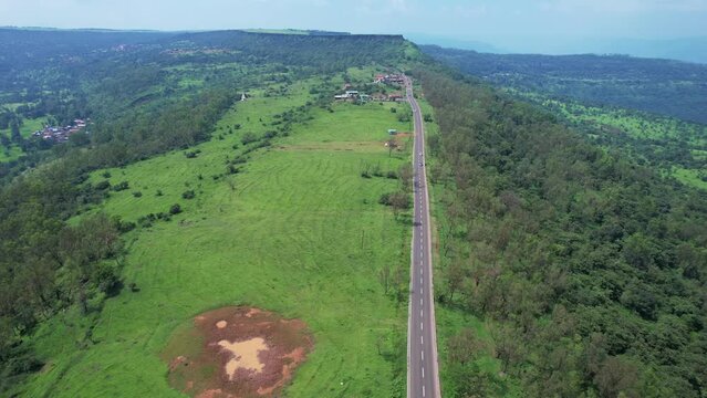 Aerial view of a road amidst green monsoon surroundings with traffic leading to Kaas valley near Satara India.