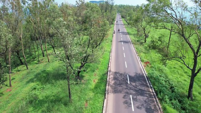 Aerial view of a road amidst green monsoon surroundings with traffic leading to Kaas valley near Satara India.