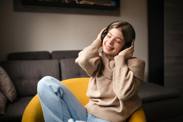 Young beautiful woman in autumn outfit enjoying the music at home