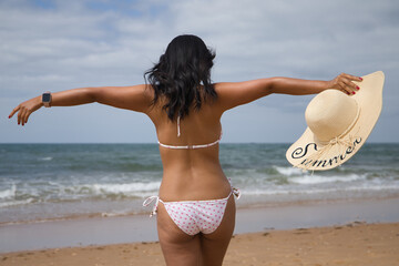 South American woman, young and beautiful, brunette with bikini and hat with the word summer held...