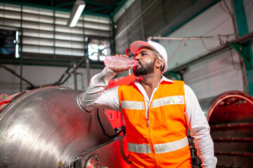 Professional engineers with helmets work to maintain industrial construction equipment. The worker...