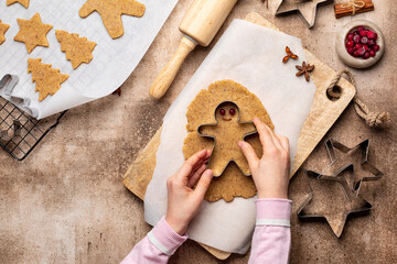 Cooking Christmas cookies, gingerbread man with cutter. Made with hazelnut butter. Girls hands. Christmas and New Year traditions concept, view from above.