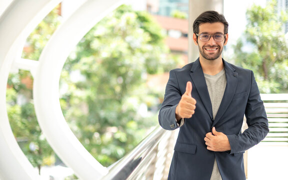 The Portrait Of Happy Young Handsome Caucasian Businessman With Eyeglasses And Wearing Deep Blue Suits For Professional Look.