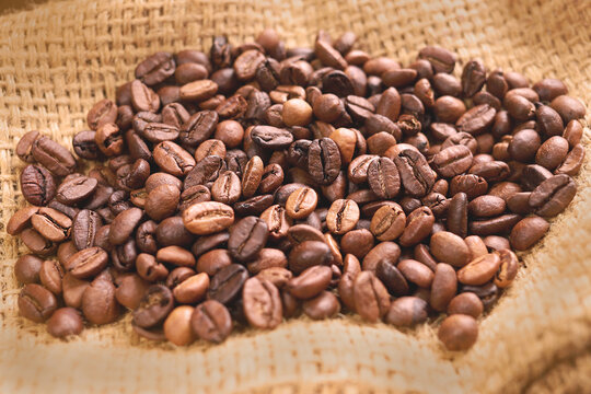 Coffee beans of medium roast coffee on on sackcloth. Arabica roast coffee beans. Toning drink, natural energetic. Beans closeup, coffee beans background. Espresso aroma, caffeine drink