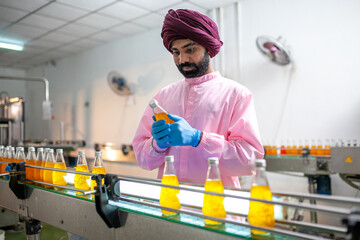 Asian man worker with clipboard is checking product bottles of fruit juice on the production line in the beverage factory. Manufacturer checks quality of food industry. - 540638029
